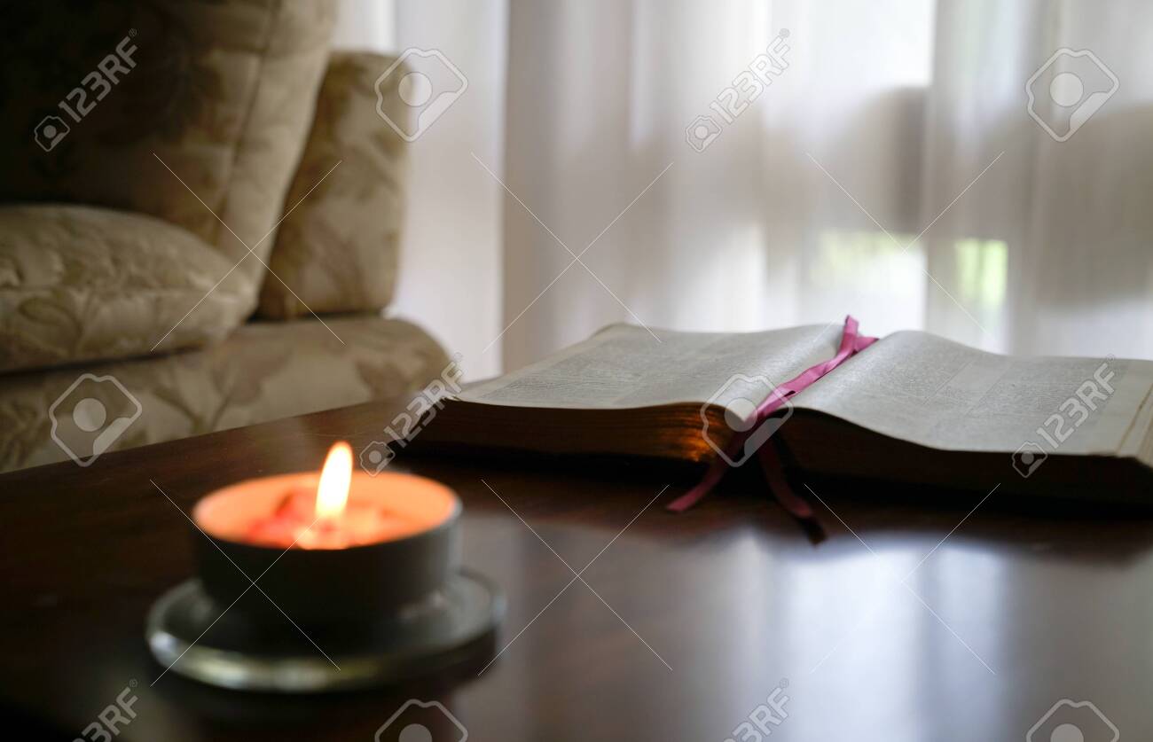 Lectio Divina: guia prática em quatro passos para rezar com a Bíblia 7 Bíblia aberta sobre mesa de madeira com vela acesa e ambiente silencioso
