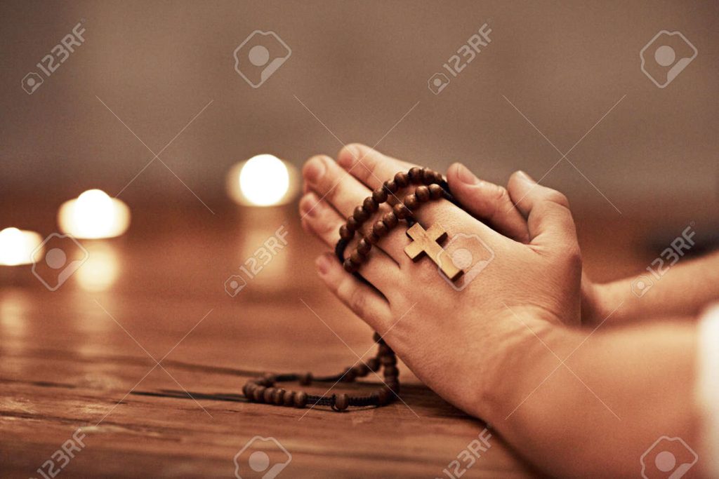 Orações populares e orações oficiais: o que a Igreja permite e quando há superstição 6 190258468 person hands praying holding a rosary with cross of christian faith religion or tradition in a