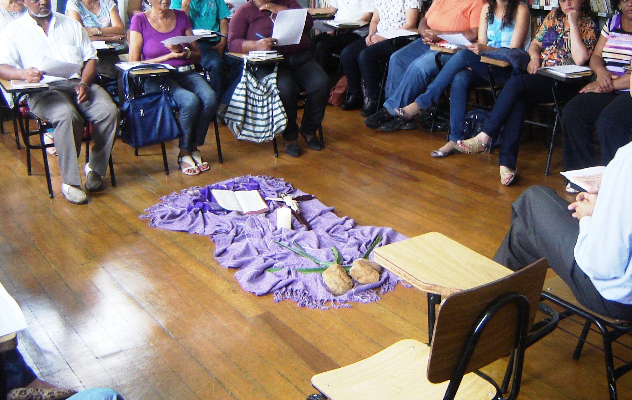 equipe de liturgia reunida preparando repertório com folheto e bíblia sobre mesa