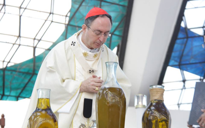 sacerdote segurando um pequeno frasco de óleo santo durante a liturgia