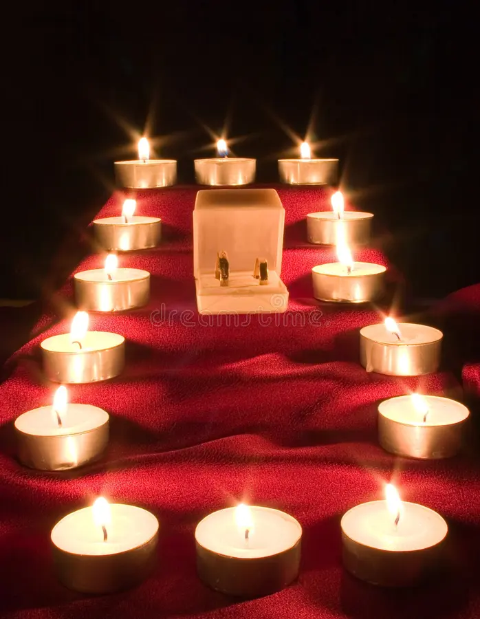 alianças de casamento sobre mesa com vela acesa