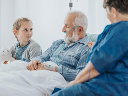 familia junto ao leito de um doente grave num hospital