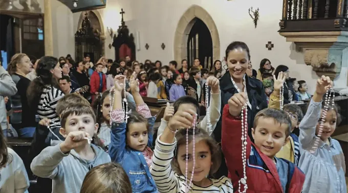 Grupo de fiéis rezando o terço em círculo numa capela